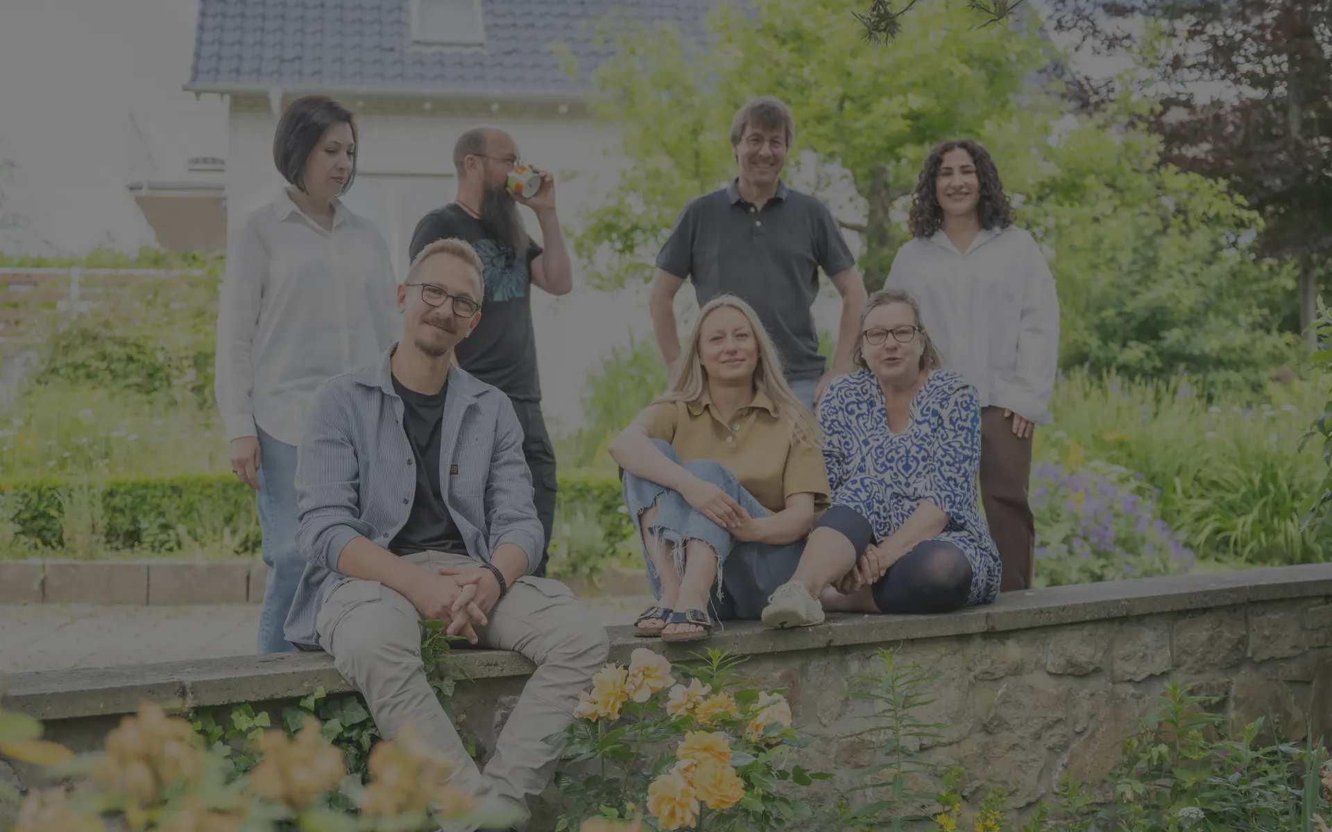 Gruppenfoto des Teams Espey, entspannt auf einer Gartenmauer sitzend.