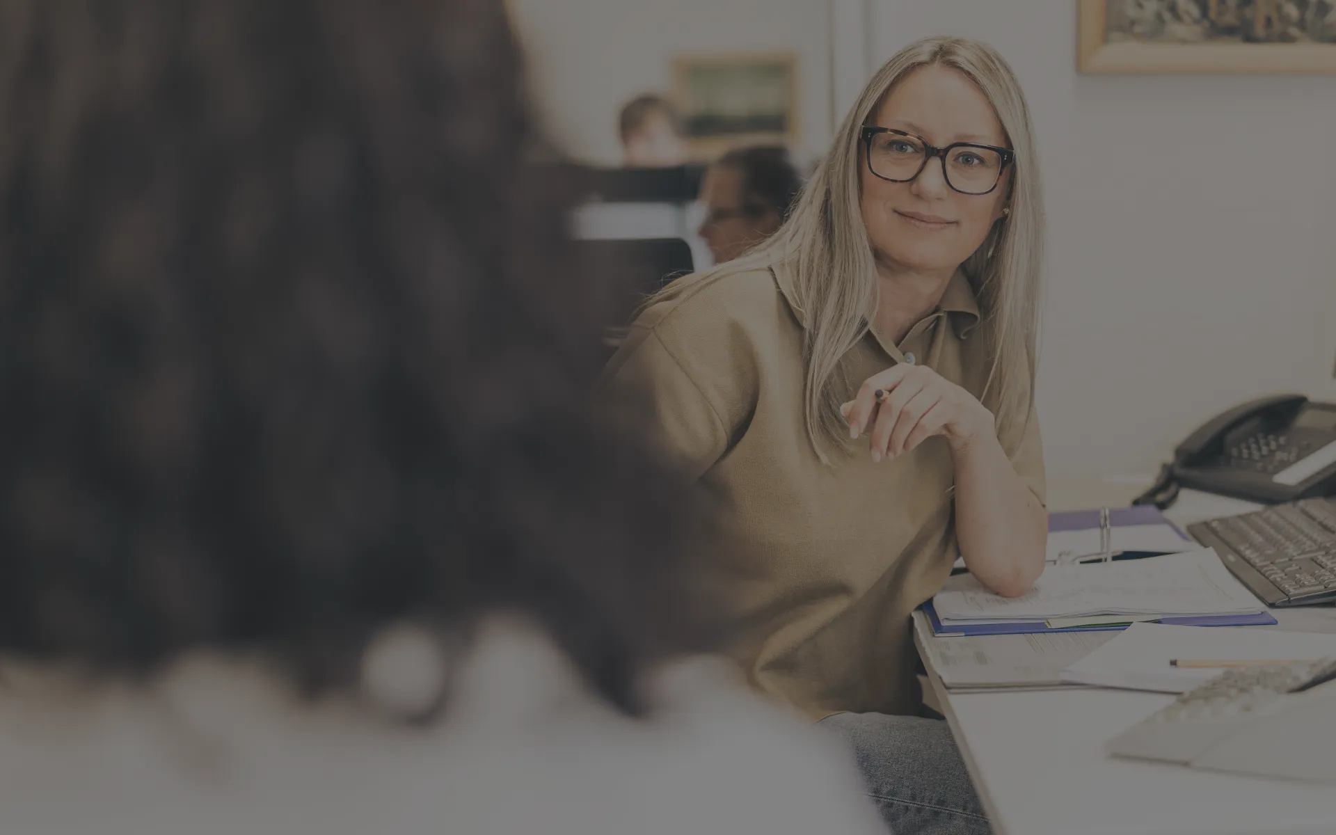 Eine Steuerberaterin berät eine Kundin an ihrem Schreibtisch.