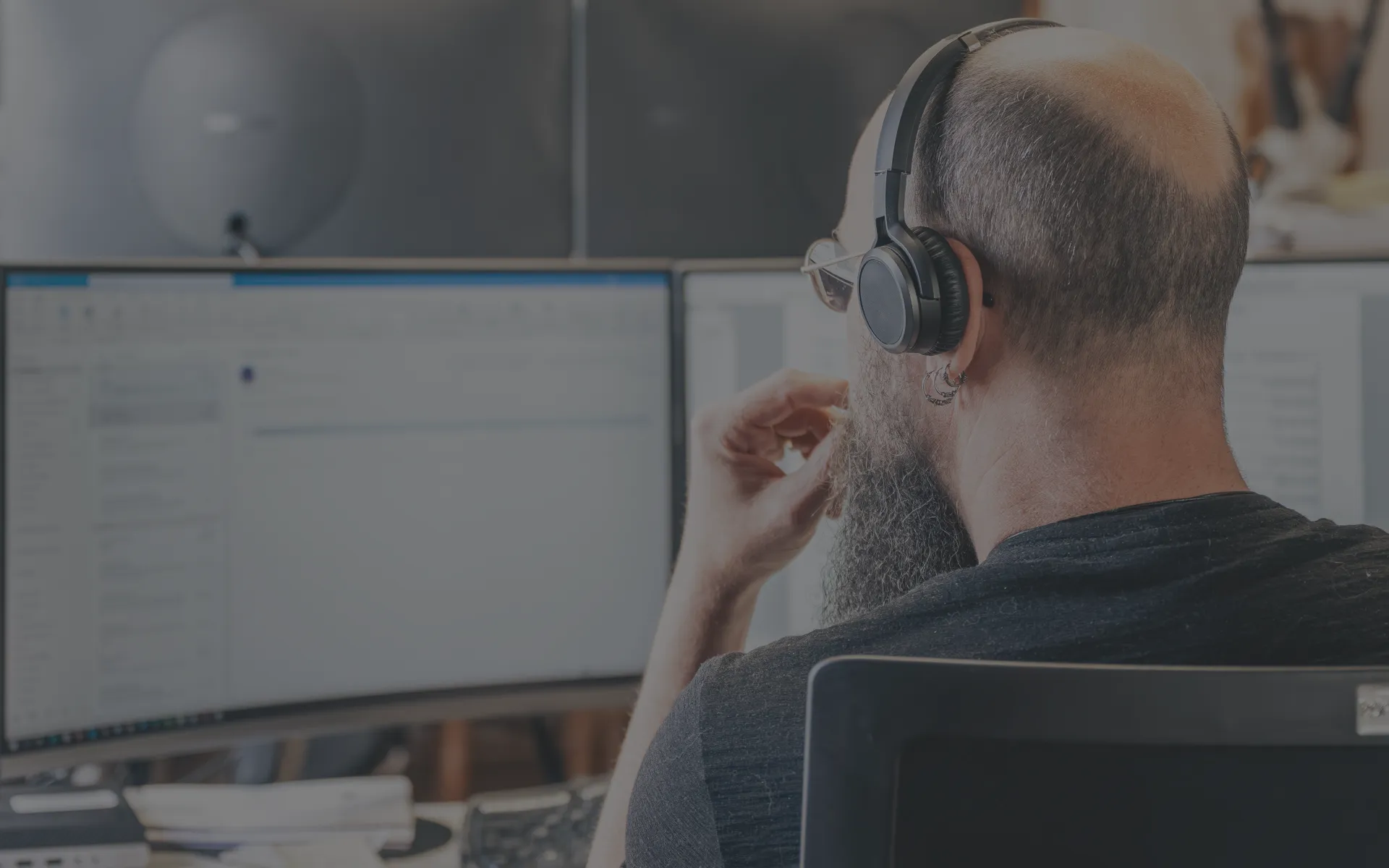 Ein Steuerberater arbeitet am PC und hört dabei Musik über Kopfhörer.