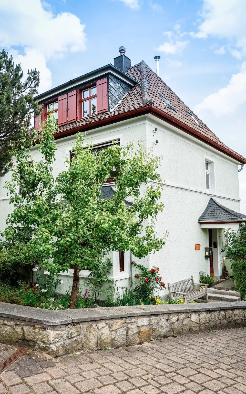 Ein weißes Familienhaus mit einem bunten Garten drumherum dient als Sitz der Steuerkanzlei Espey.