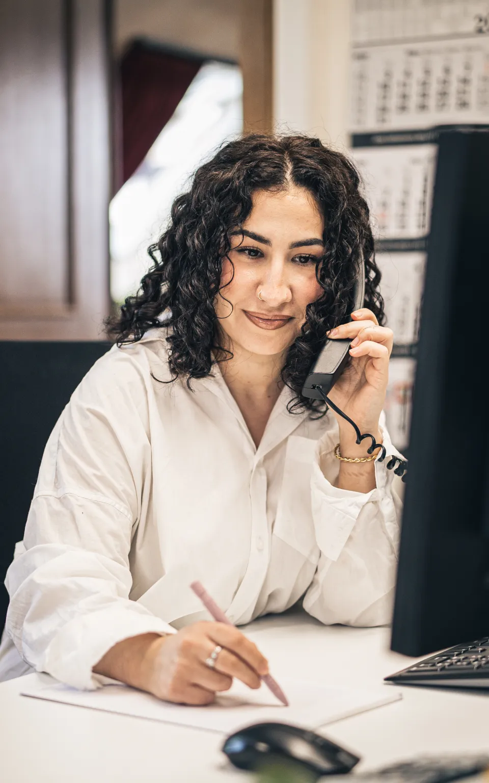 Eine Mitarbeiterin macht Notizen während eines Telefonats.
