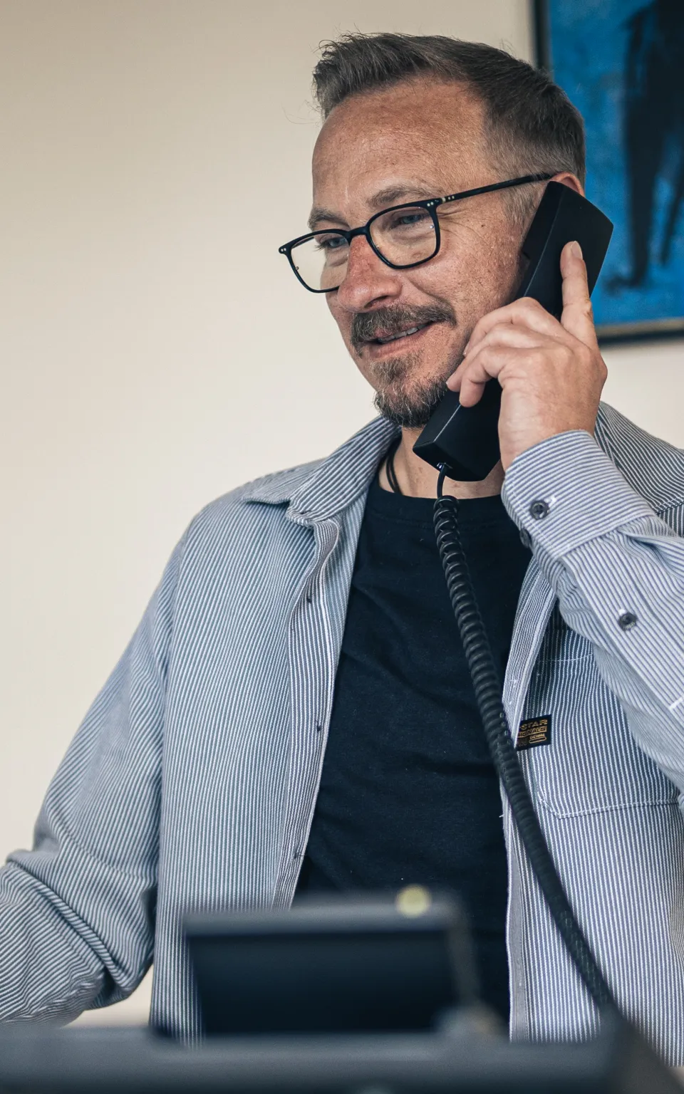 Herr Espey führt ein Telefongespräch und hat dabei einen Telefonhörer am Ohr.