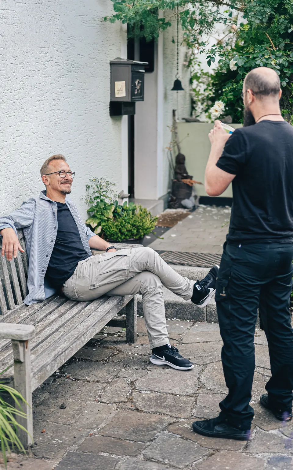 Entspannt sitzt Herr Espey auf einer Gartenbank vor dem Familienhaus und unterhält sich locker mit einem Kollegen.