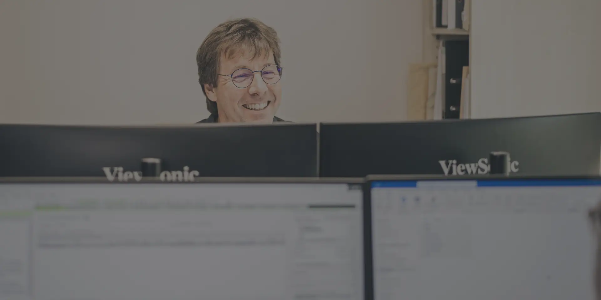 Ein Steuerberater lächelt entspannt hinter seinem PC-Monitor.