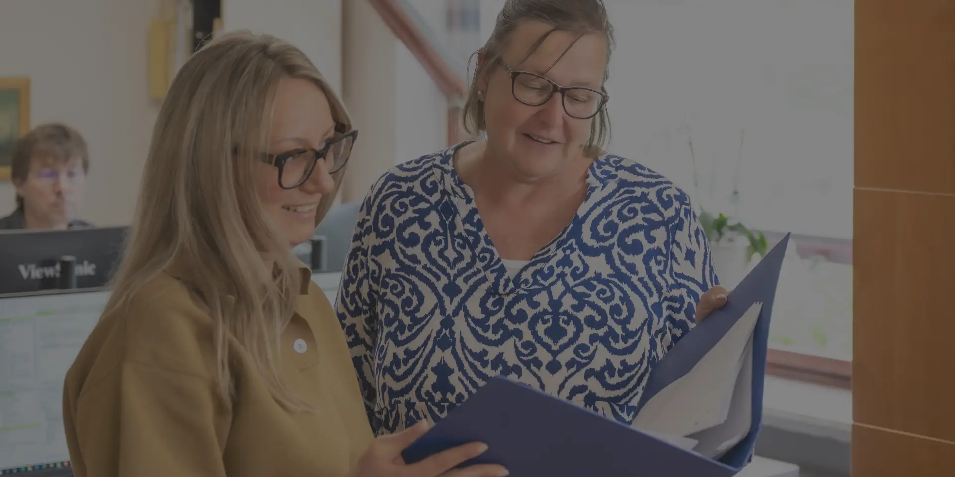 Zwei Kolleginnen tauschen sich über eine Akte aus.